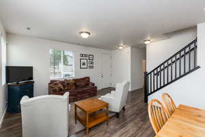 Living room with stairs and dark wood-style flooring