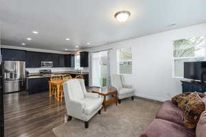 Living area with dark wood-type flooring and recessed lighting