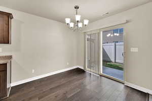 Unfurnished dining area featuring a chandelier and dark wood-style floors