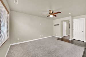Spare room featuring dark colored carpet and ceiling fan