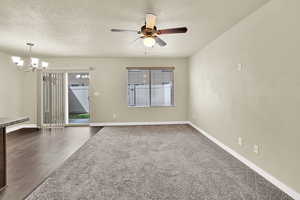 Unfurnished room with a textured ceiling, ceiling fan, and hanging lights