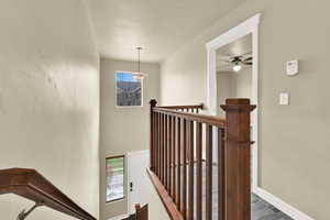 Stairway featuring a textured ceiling and baseboards