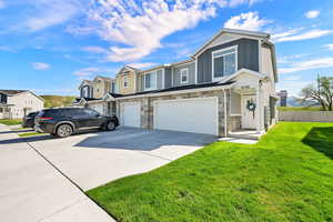 View of front of home with stone siding, board and batten siding, a garage, driveway, and a residential view