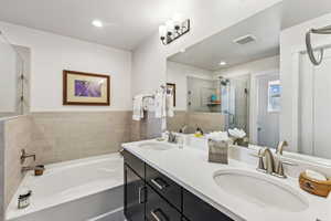 Full bathroom featuring double vanity, a garden tub, and a stall shower