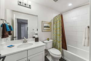 Full bathroom with vanity, shower / bath combo with shower curtain, and recessed lighting