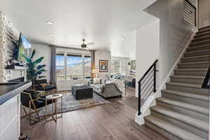 Living area with a stone fireplace, a ceiling fan, hardwood / wood-style floors, and recessed lighting