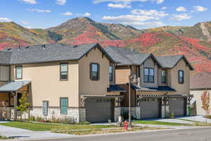 View of front of house with a garage, stone siding, a mountain view, and stucco siding