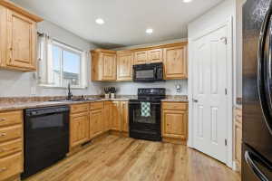 Kitchen featuring black appliances, light wood-style flooring, recessed lighting, light wood finish cabinetry, and light stone counters