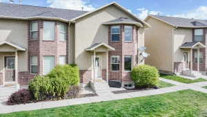 Traditional-style house with stucco siding, brick siding, a front lawn, and entry steps