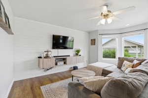 Living area featuring wood finished floors, a ceiling fan, an accent wall, wood walls, and recessed lighting
