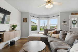Living room featuring ceiling fan, dark wood finished floors, recessed lighting, and wooden walls