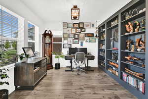 Home office with dark wood-style flooring and built in features