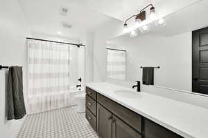 Bathroom featuring vanity, shower / bath combination with curtain, light tile patterned floors, and a textured ceiling