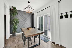 Dining room with an accent wall, light wood-style floors, hanging lights, and a decorative wall