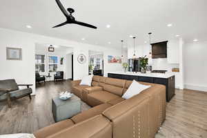 Living area featuring light wood-type flooring, a ceiling fan, and recessed lighting