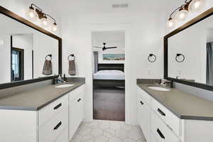 Ensuite bathroom with two vanities, light carpet, light tile patterned floors, and a ceiling fan