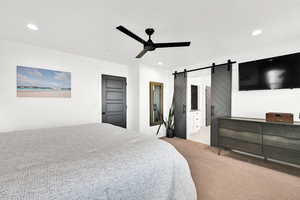 Bedroom featuring a barn door, carpet flooring, ceiling fan, connected bathroom, and recessed lighting