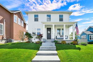 View of front of home with covered porch and a front yard