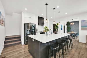 Two tone kitchen with a spacious island, stainless steel appliances, a kitchen breakfast bar, dual tone cabinetry, and light wood-type flooring