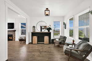Sitting room with hardwood / wood-style floors and a warm lit fireplace