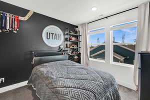 Bedroom with freestanding refrigerator and light carpet