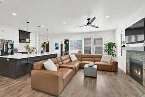 Living room featuring a brick fireplace, light wood-style flooring, recessed lighting, and ceiling fan