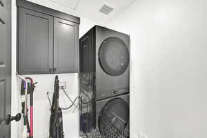 Laundry room with stacked washer / drying machine and cabinet space