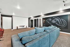 Home theater room featuring light colored carpet and baseboards