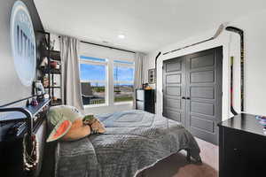 Bedroom with light carpet, a closet, and freestanding refrigerator