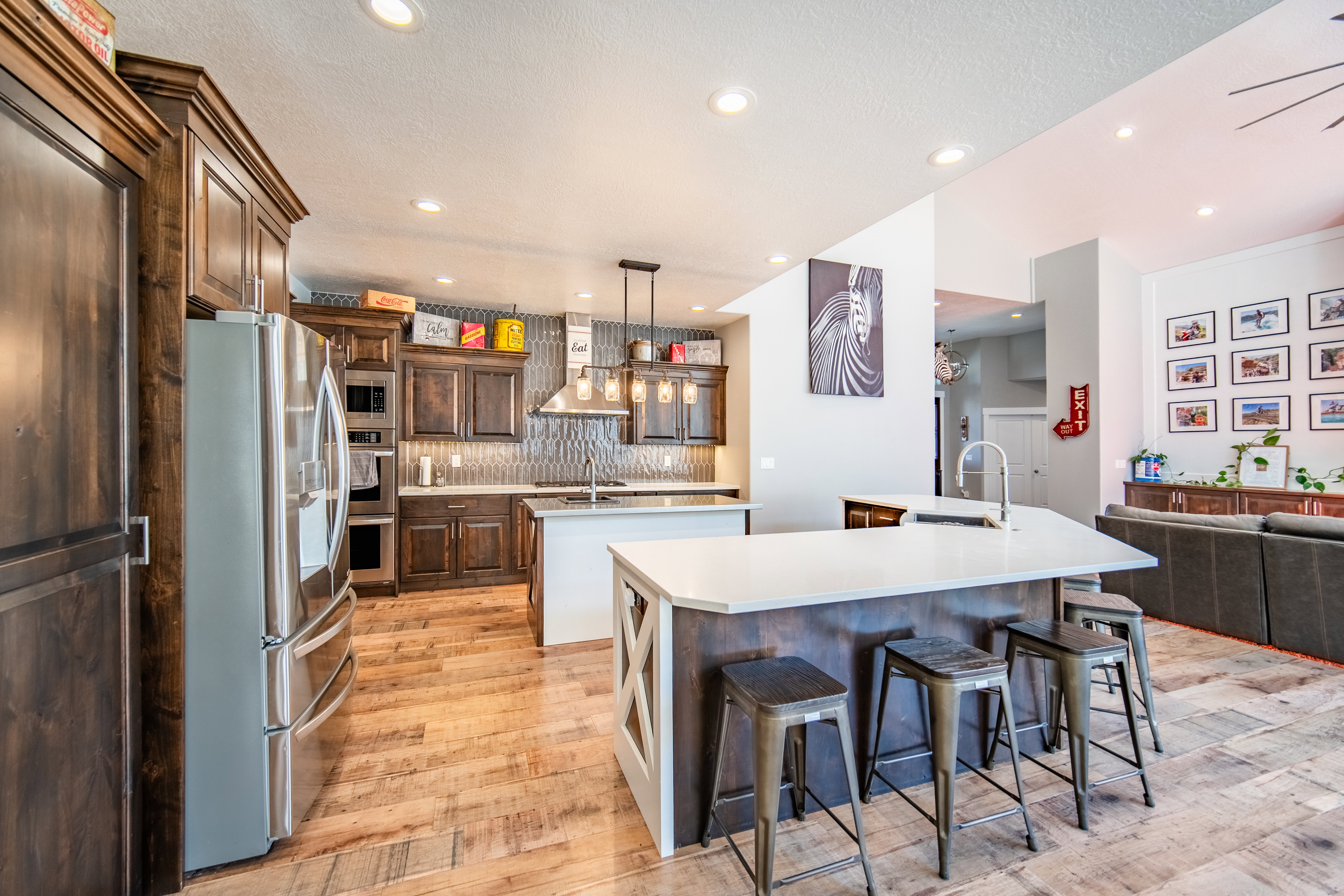 Kitchen with stainless steel appliances, a kitchen breakfast bar, prep island, open floor plan, wood-type flooring, and light stone countertops