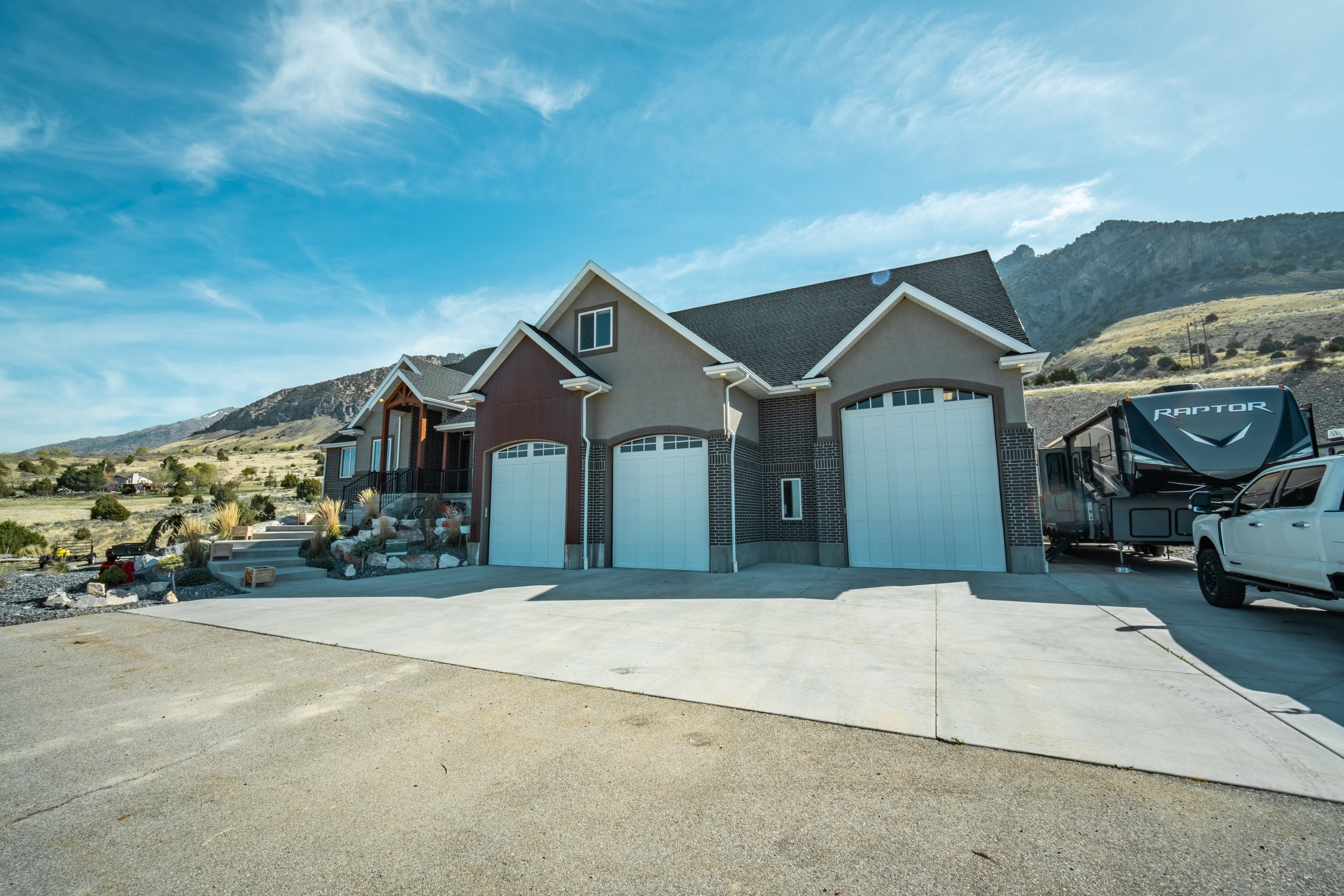 View of front of home with a mountain view, stucco siding, concrete driveway, and a garage