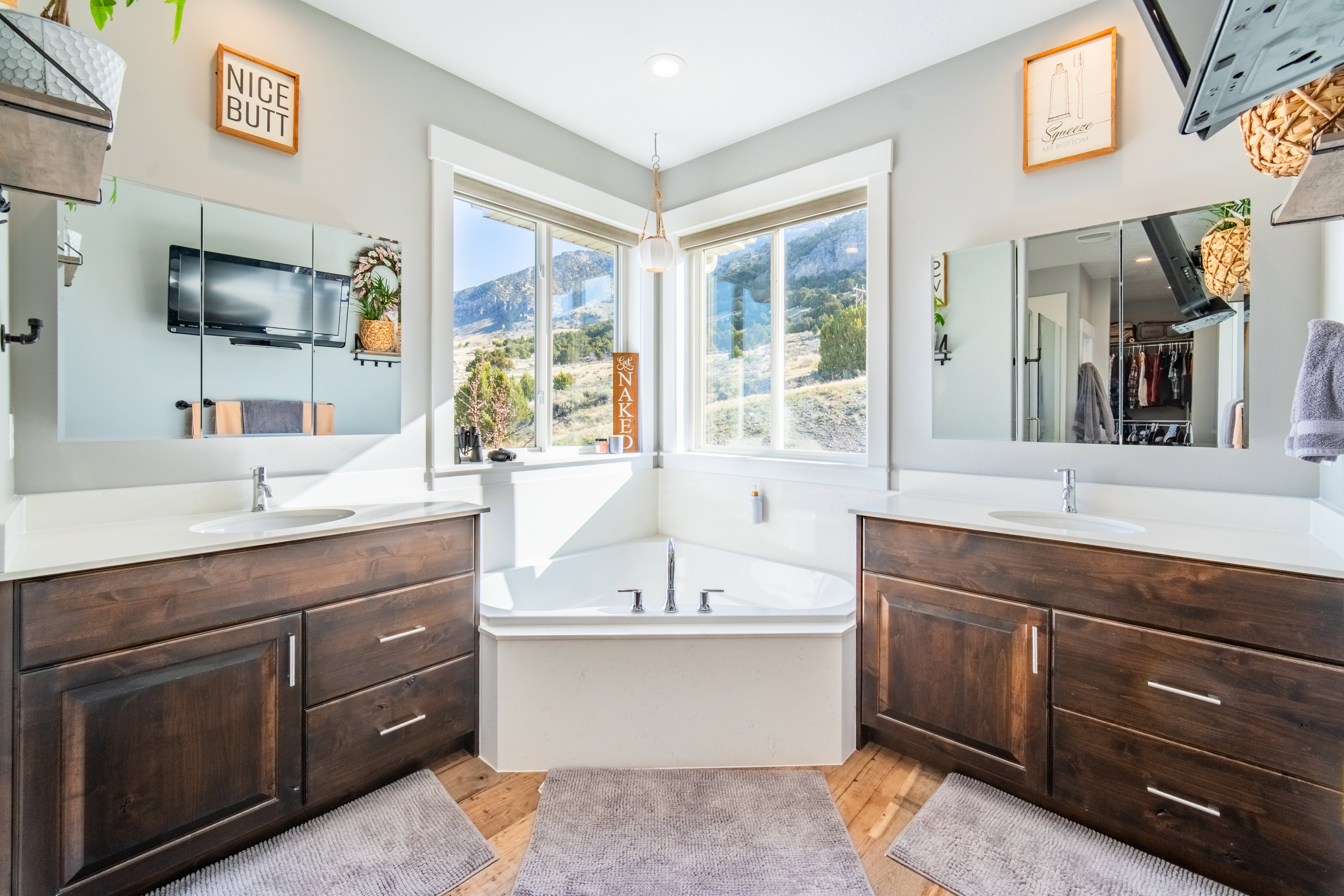 Full bath with a bath, two vanities, and light wood-style flooring