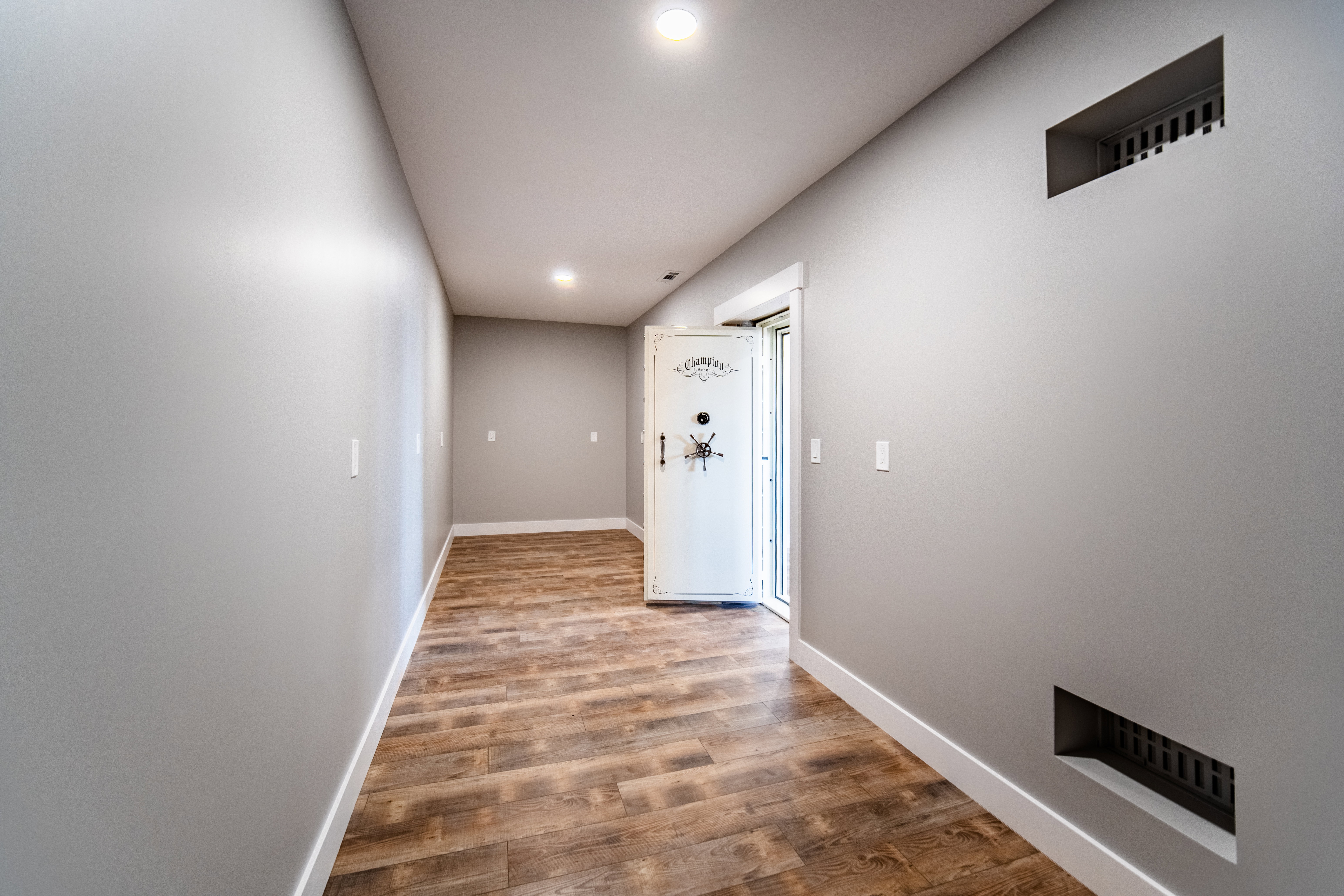 Safe room featuring four concrete walls, sealed safe door, wood finished floors, and recessed lighting