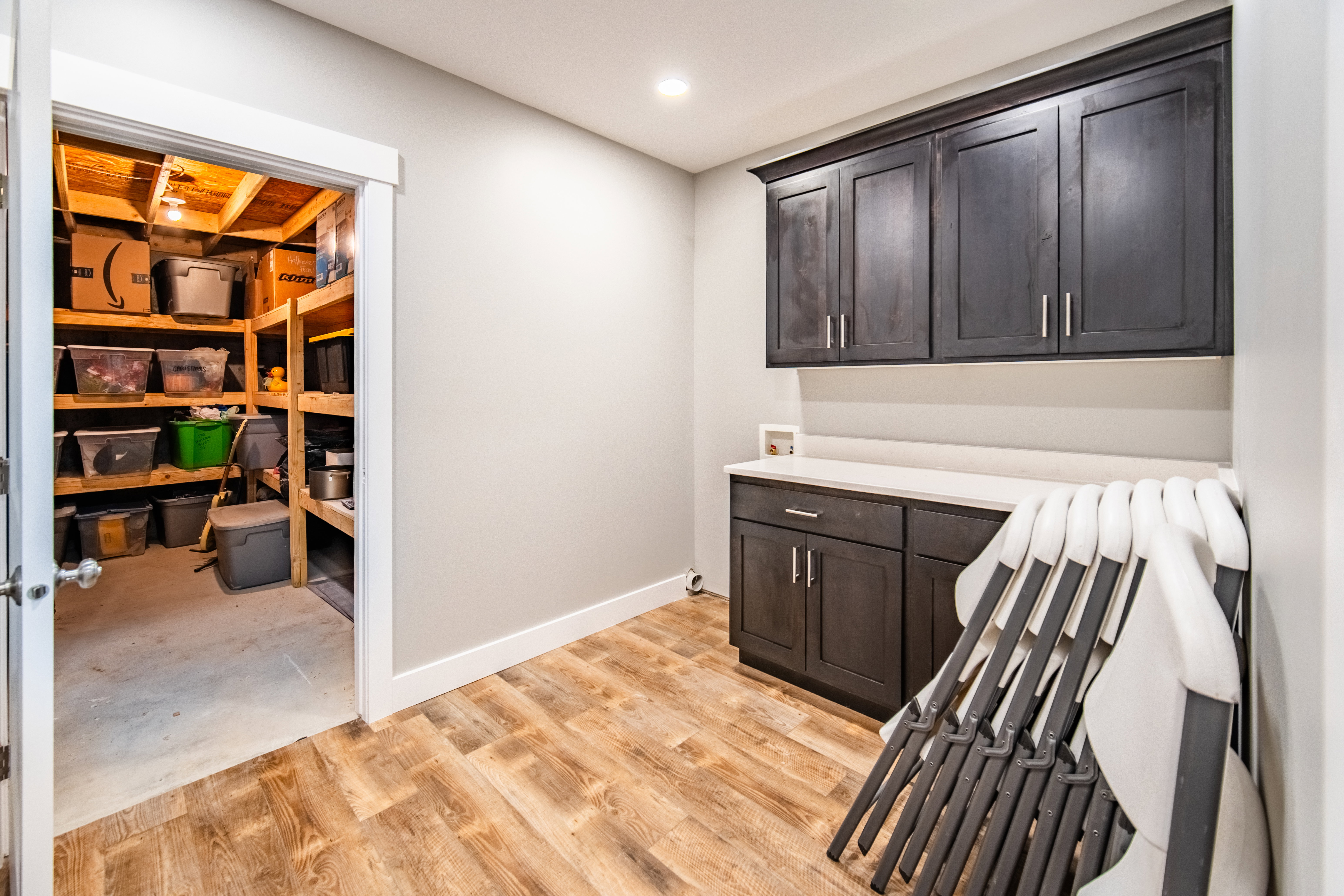 Laundry area and cold storage access with cabinet space, washer hookup, recessed lighting, and wood-type flooring