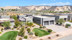 View of front of house with a mountain view, driveway, a garage, stucco siding, and a front yard