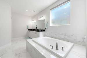 Full bathroom with double vanity, a bath, and light marble finish flooring