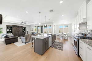 Two tone kitchen featuring a barn door, stainless steel appliances, a kitchen bar, two tone cabinetry, and open floor plan
