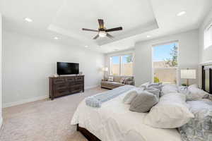 Bedroom with light colored carpet, ceiling fan, recessed lighting, and a raised ceiling