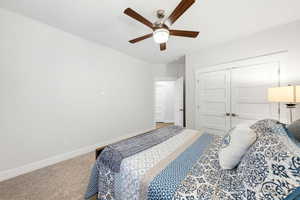 Carpeted bedroom featuring a ceiling fan and a closet
