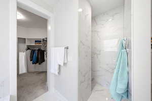 Full bathroom with a walk in closet, a marble finish shower, and light marble finish floors