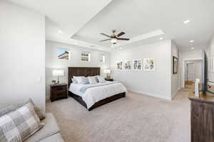 Bedroom with light carpet, a ceiling fan, a tray ceiling, and recessed lighting