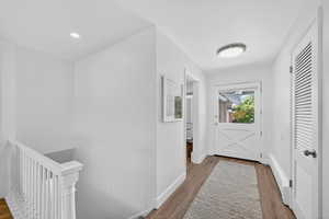 Corridor with wood finished floors and an upstairs landing