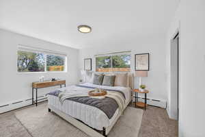 Bedroom with a baseboard radiator and light colored carpet