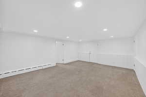 Finished basement featuring carpet floors, recessed lighting, wainscoting, and baseboard heating