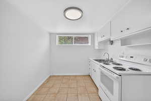 Kitchen with white electric range oven, light countertops, and white cabinets