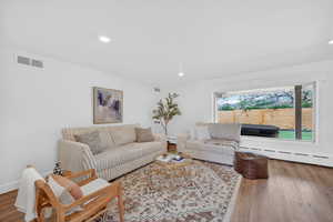 Living area featuring hardwood / wood-style floors, a baseboard heating unit, and recessed lighting