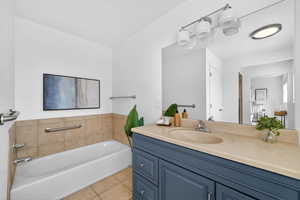 Bathroom featuring vanity, a bath, and light tile patterned flooring