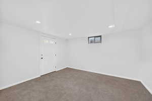 Basement with recessed lighting and dark colored carpet