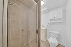 Bathroom featuring vanity, a shower stall, a textured ceiling, and light tile patterned floors