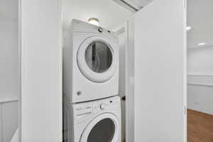 Laundry area featuring stacked washer and dryer, recessed lighting, wainscoting, and carpet flooring